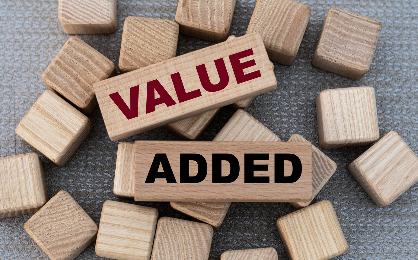 VALUE ADDED - words on wooden bars on cubes on a gray background